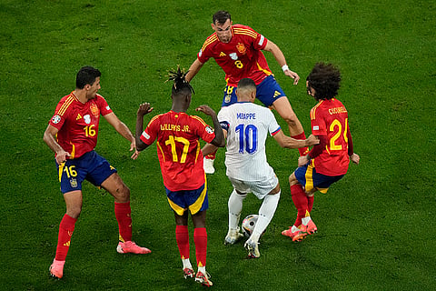 Kylian Mbappe dribbles the ball surrounded by Spain's players 